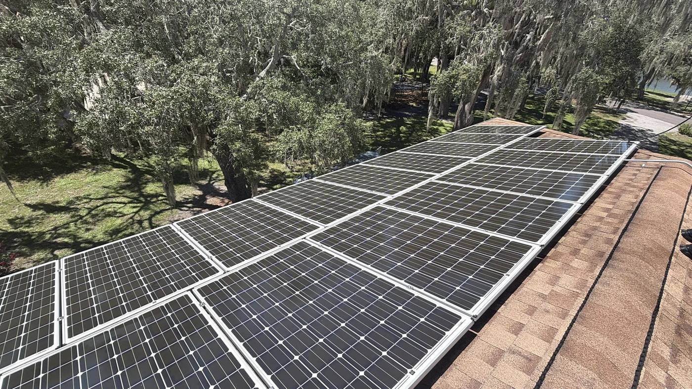 Freshly cleaned solar array on a shingle roof under live oak trees