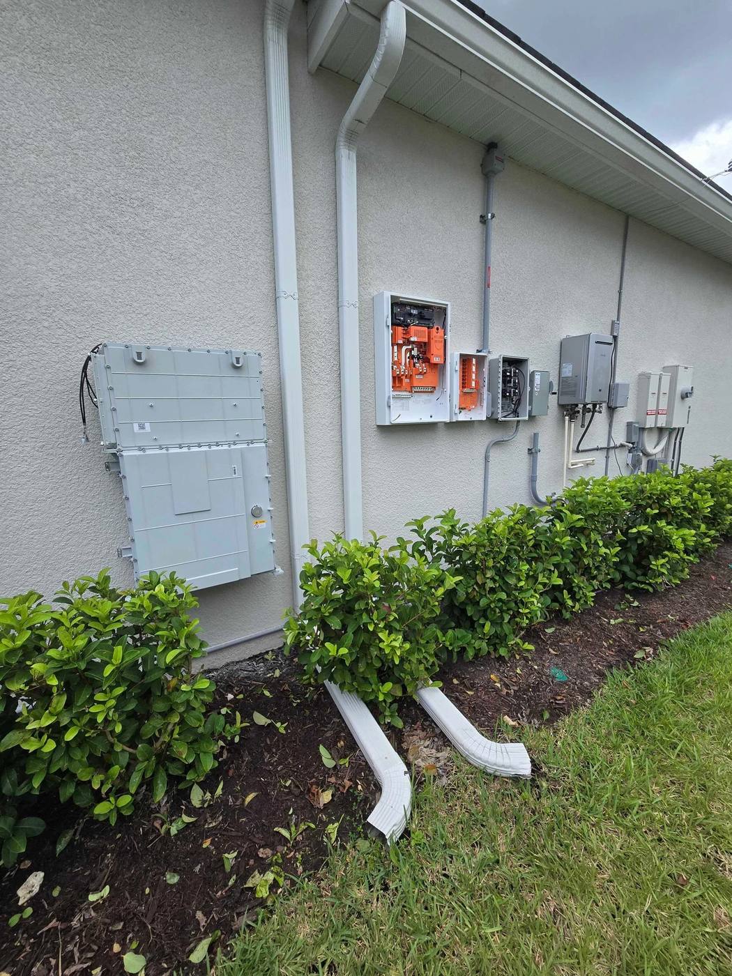 Solar inverter, disconnect and electrical panels mounted on the side of a stucco home