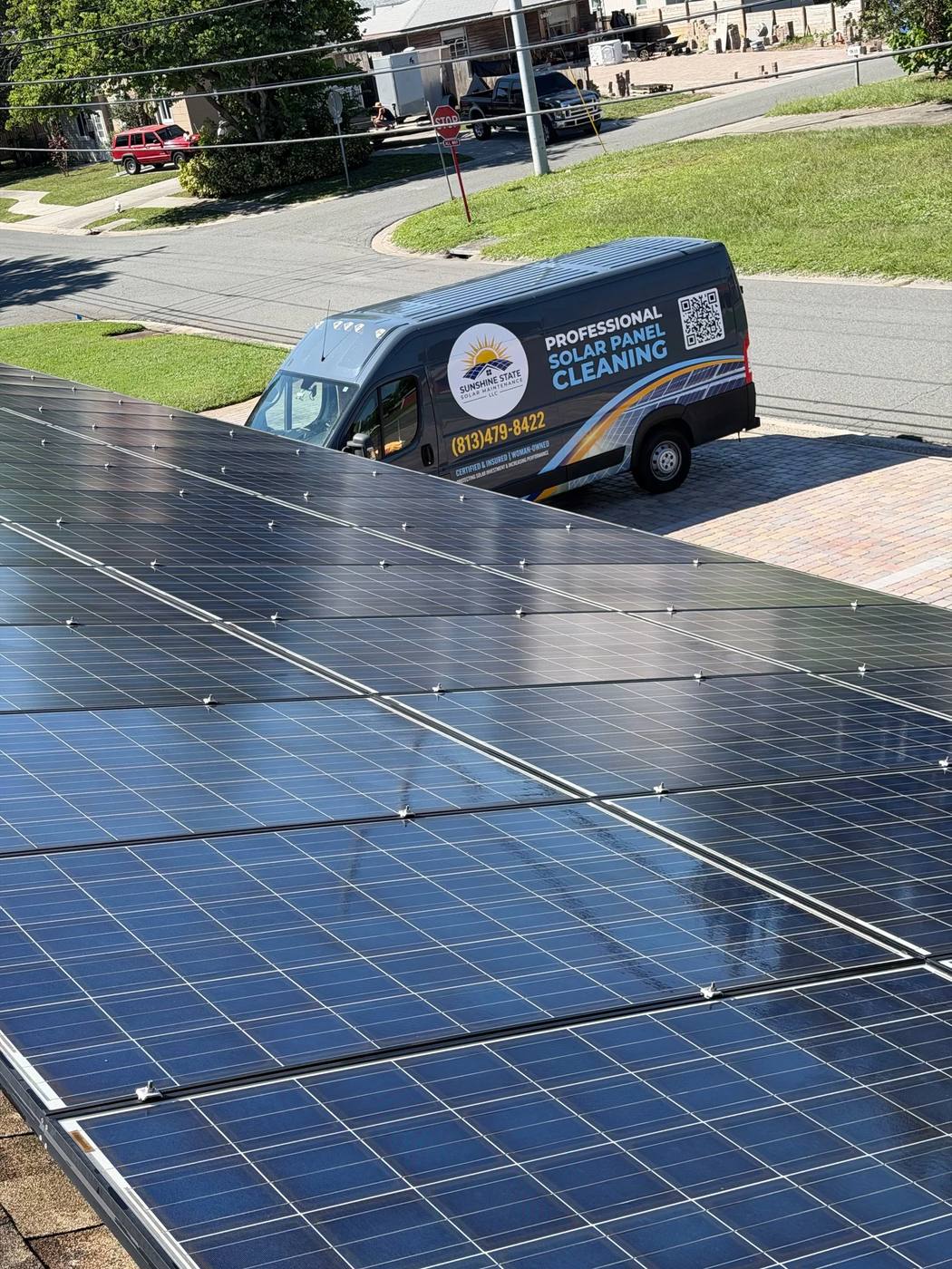 Clean solar array with the Sunshine State Solar Maintenance van parked in the driveway below